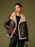 Woman wearing a brown leather jacket with beige fur lining against a green background